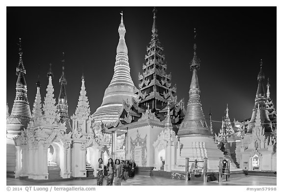 Women walking, stupas, shrines, and Main Stupa at night, Shwedagon Pagoda. Yangon, Myanmar (black and white)