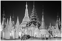 Women walking, stupas, shrines, and Main Stupa at night, Shwedagon Pagoda. Yangon, Myanmar ( black and white)