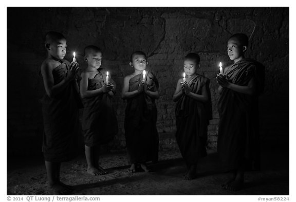 Five novices standing in circle inside temple with candles. Bagan, Myanmar (black and white)