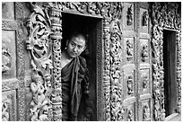 Exquisitely carved teak walls and monk pearing, Shwe In Bin Kyaung pagoda. Mandalay, Myanmar ( black and white)