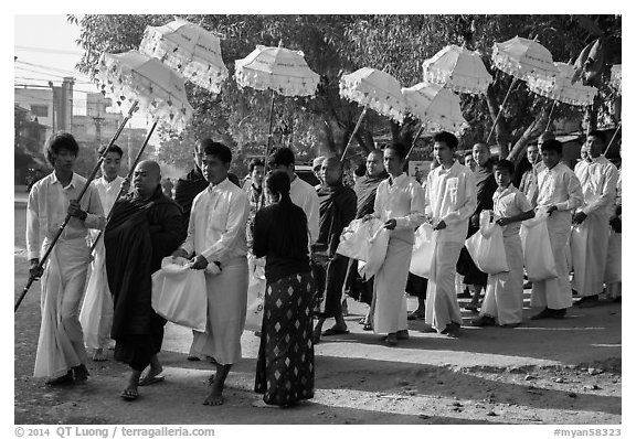 Umbrella bearer, Monks, and donation holders in alms procession. Mandalay, Myanmar (black and white)