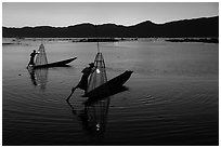 Leg-rowing Intha fishermen with lanterns at dusk. Inle Lake, Myanmar ( black and white)