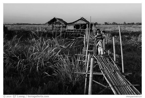 Family walking out of stilt house on precarious bridge. Inle Lake, Myanmar (black and white)