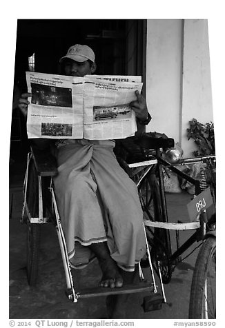Cyclo driver reading newspaper with picture of QT Luong tour group. Bago, Myanmar (black and white)