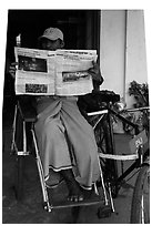 Cyclo driver reading newspaper with picture of QT Luong tour group. Bago, Myanmar ( black and white)