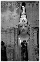 Monumental Buddha image seen between walls,  Wat Si Chum. Sukothai, Thailand (black and white)
