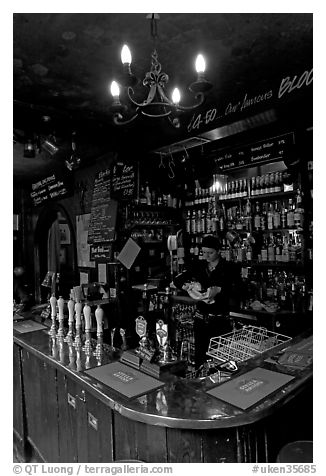 Woman cleaning glass at the bar, pub The Grenadier. London, England, United Kingdom (black and white)