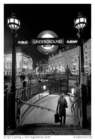 Woman with shopping bag entering subway at night, Piccadilly Circus. London, England, United Kingdom (black and white)