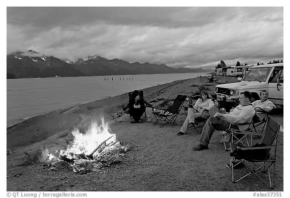 Sitting by campfire at midnight, waterfront campground. Seward, Alaska, USA (black and white)