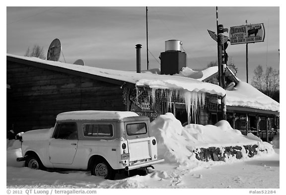Old truck parked next to lodge in winter. Alaska, USA (black and white)