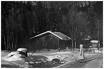 Woman with winter coat walking on path to cabins. Chena Hot Springs, Alaska, USA ( black and white)