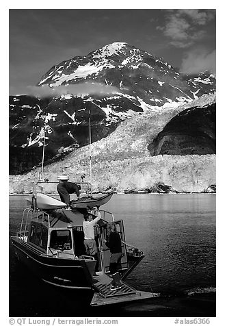 Kayakers unloading from the water taxi at Black Sand Beach. Prince William Sound, Alaska, USA (black and white)