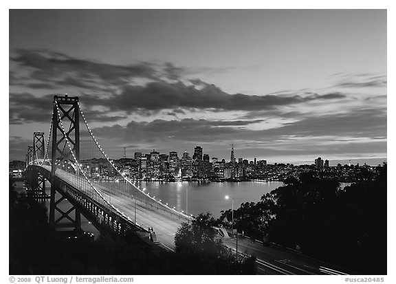 Bay Bridge and city skyline with lights at sunset. San Francisco, California, USA