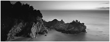 Seascape at sunset with coastal waterfall. Big Sur, California, USA (Panoramic black and white)