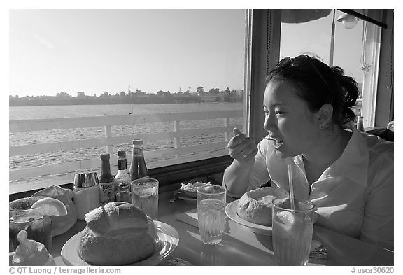 Woman eating clam chowder in a sourdough bread bowl. Santa Cruz, California, USA