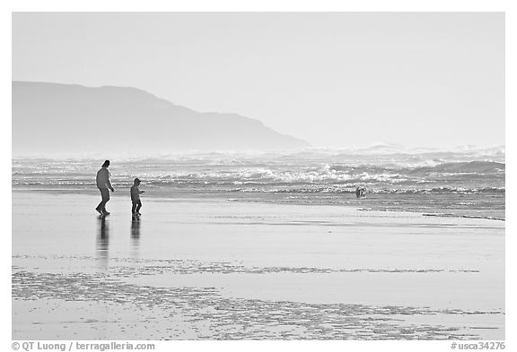 Man and child on wet beach, afternoon. San Francisco, California, USA (black and white)