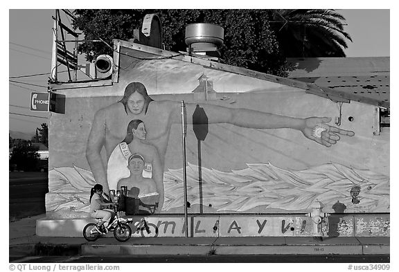 Hispanic girl on bicycle and mural, Alviso. San Jose, California, USA (black and white)