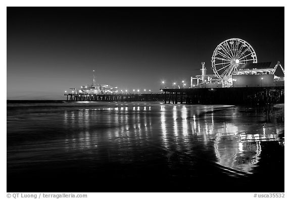 Ferris Wheel and pier reflected on wet sand at night. Santa Monica, Los Angeles, California, USA