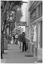 People looking at store display on Main Street. Half Moon Bay, California, USA ( black and white)