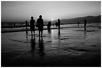 People and reflections on beach at sunset, Santa Monica Beach. Santa Monica, Los Angeles, California, USA (black and white)