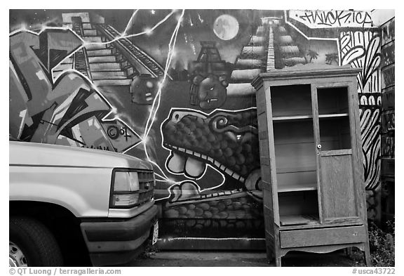 Car, mural, and discarded furniture, Mission District. San Francisco, California, USA (black and white)