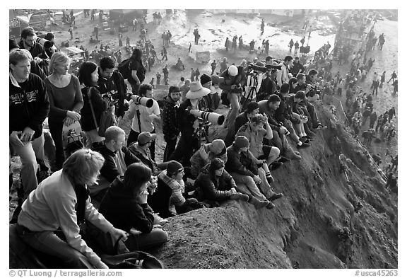 Spectators sitting on cliff to see mavericks contest. Half Moon Bay, California, USA (black and white)