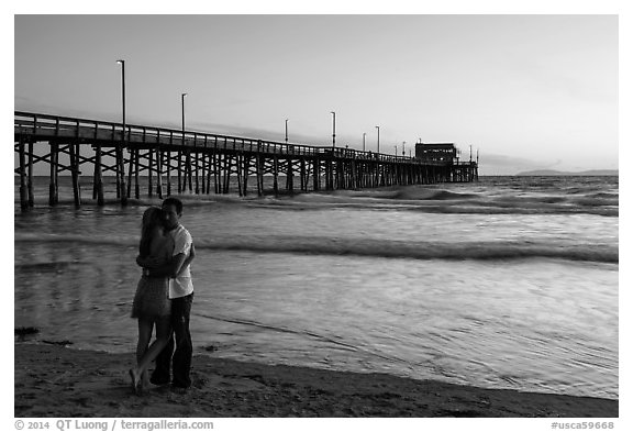 Couple embracing in front of Newport Pier. Newport Beach, Orange County, California, USA (black and white)