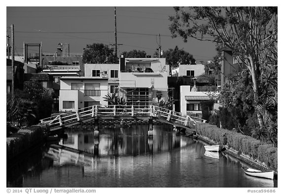 Rower under bridge next to colorful houses. Venice, Los Angeles, California, USA (black and white)