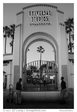 Men roll red carpet in front of Universal Studios gate. Universal City, Los Angeles, California, USA (black and white)