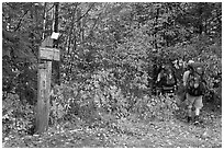 Backpackers hiking into autumn woods at Appalachian trail marker. Maine, USA ( black and white)