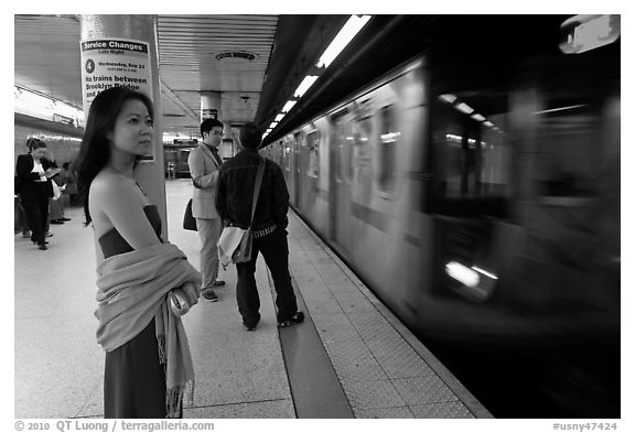 Young woman and arriving train on subway platform. NYC, New York, USA (black and white)