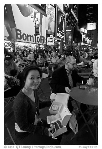Woman with cupcakes sitting on Times Squares at night. NYC, New York, USA (black and white)