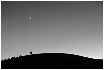 Curve of cinder cone, pastel sky, and moon. Craters of the Moon National Monument and Preserve, Idaho, USA ( black and white)