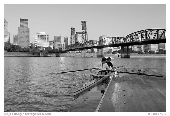 Rowers on double-oar shell lauching from deck in front of skyline. Portland, Oregon, USA (black and white)