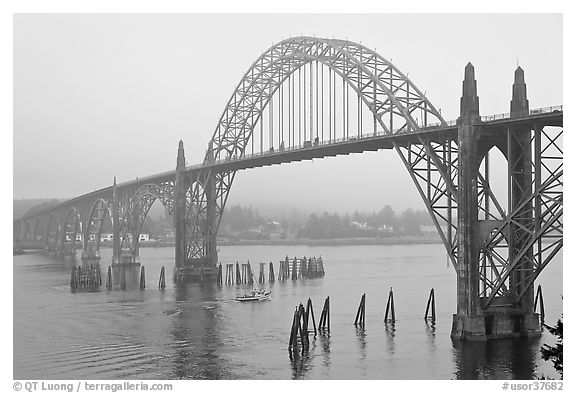 Small boat exiting harbor under Yaquina Bay Bridge. Newport, Oregon, USA (black and white)