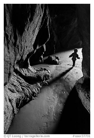 Infant walking out of sea cave. Bandon, Oregon, USA (black and white)