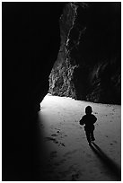 Infant walking towards the light in sea cave. Bandon, Oregon, USA ( black and white)
