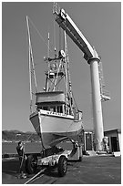 Fishing boat lifted from water by huge hoist, Port Orford. Oregon, USA (black and white)