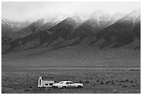 Car and pickup cover below snowy peaks. Colorado, USA ( black and white)