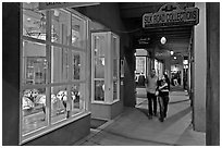 Couple walking by night in front of gallery. Santa Fe, New Mexico, USA ( black and white)
