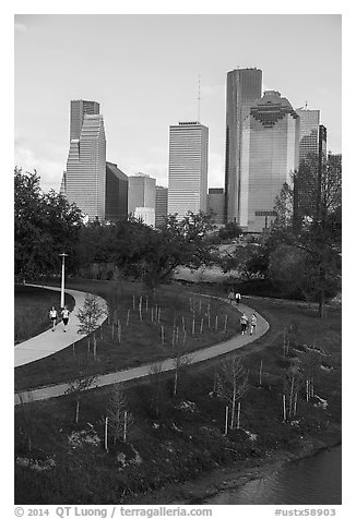 People walking in park with skyline behind. Houston, Texas, USA (black and white)