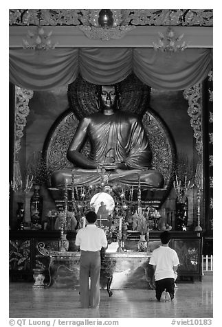 Men worshipping in front of a large Buddha state, Xa Loi pagoda, district 3. Ho Chi Minh City, Vietnam (black and white)