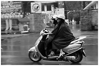 Women ride motorcycle in the rain. Ho Chi Minh City, Vietnam (black and white)