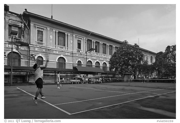 Men play tennis in front of colonial-area courthouse. Ho Chi Minh City, Vietnam (black and white)