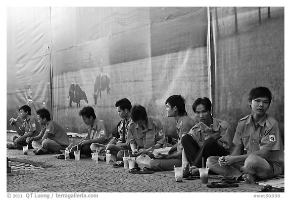 Uniformed students sitting in front of backdrops depicting traditional landscapes. Ho Chi Minh City, Vietnam (black and white)