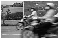 Man walking and motorbike riders blured in front of backdrops depicting traditional landscapes. Ho Chi Minh City, Vietnam ( black and white)