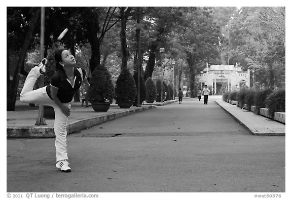 Woman plays badminton using feet (footbag), Tao Dan Park. Ho Chi Minh City, Vietnam (black and white)