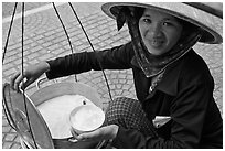 Woman smiling while handling bowl of soft tofu. Ho Chi Minh City, Vietnam (black and white)