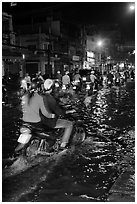 Couple riding motorcycle on flooded street at night. Ho Chi Minh City, Vietnam (black and white)
