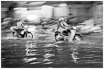 Motion-blured exposure of riders on flooded street at night. Ho Chi Minh City, Vietnam (black and white)